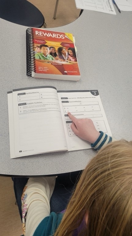 A child pointing at a book

Description automatically generated, Picture